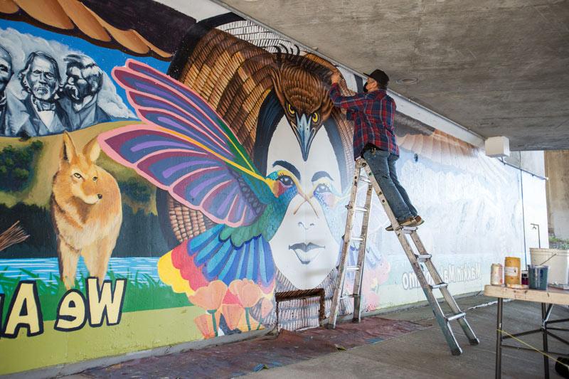 Alfonso Salazar on a ladder painting his mural.